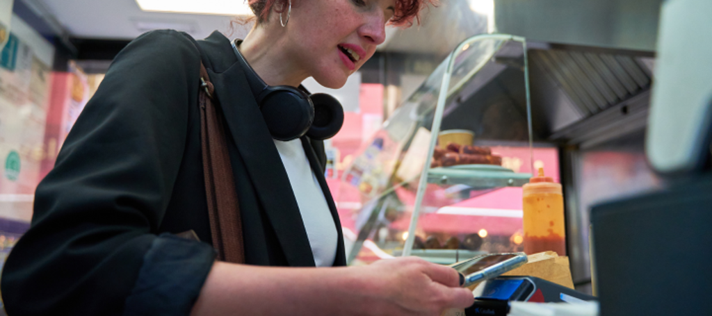 vrouw betaalt in snackbar met telefoon