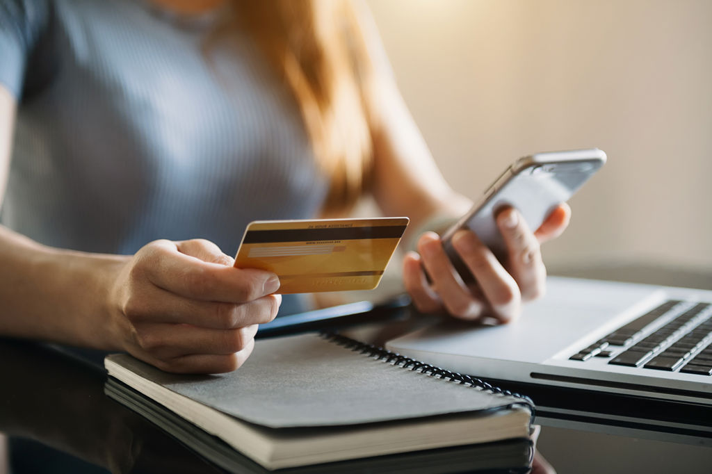 Vrouw met bankpas en telefoon in handen.