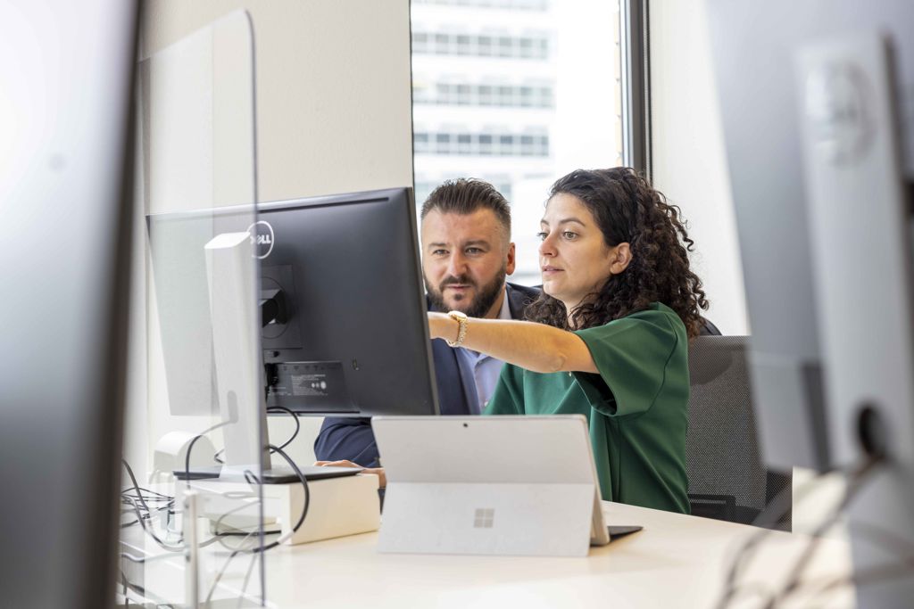 Twee NVB collega's kijkend naar een computerscherm.