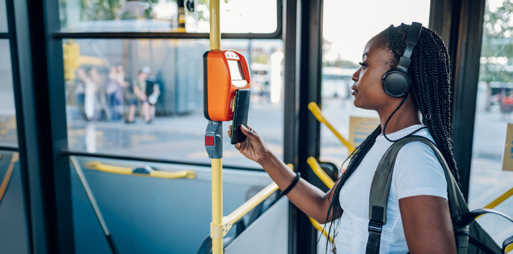 Vrouw in de bus die uitcheckt met haar telefoon. 