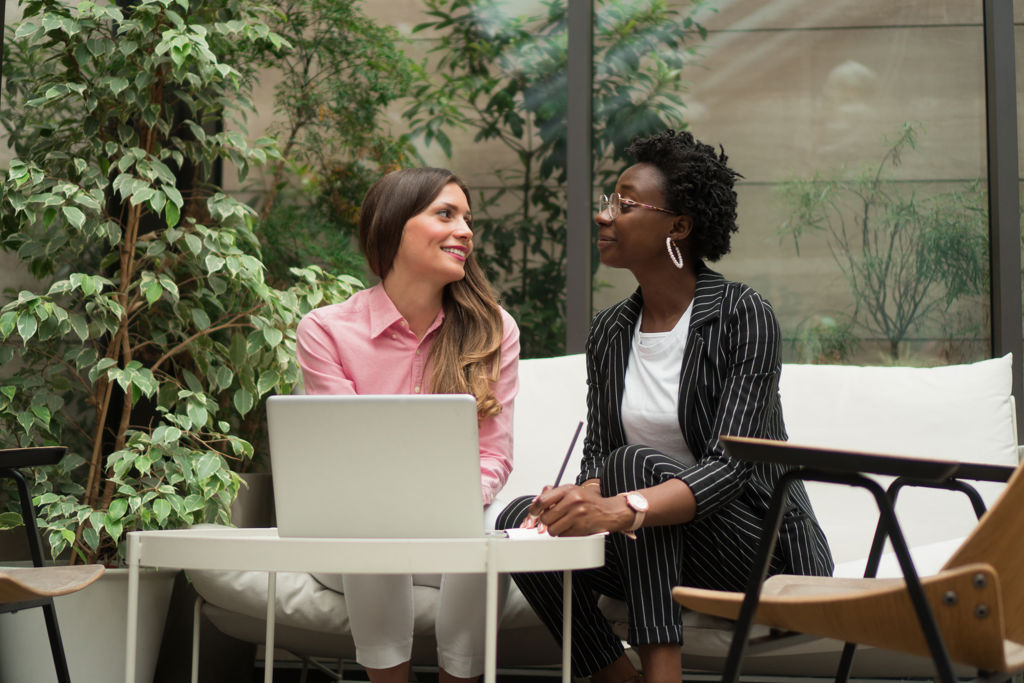 twee vrouwen in gesprek achter laptop