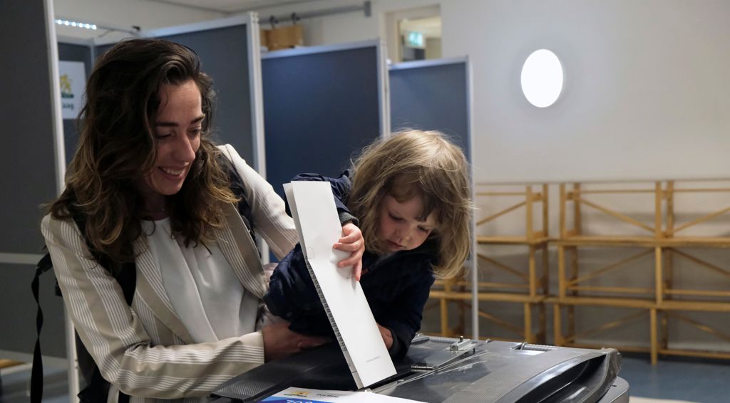 Vrouw met kind doet stembrief in bak