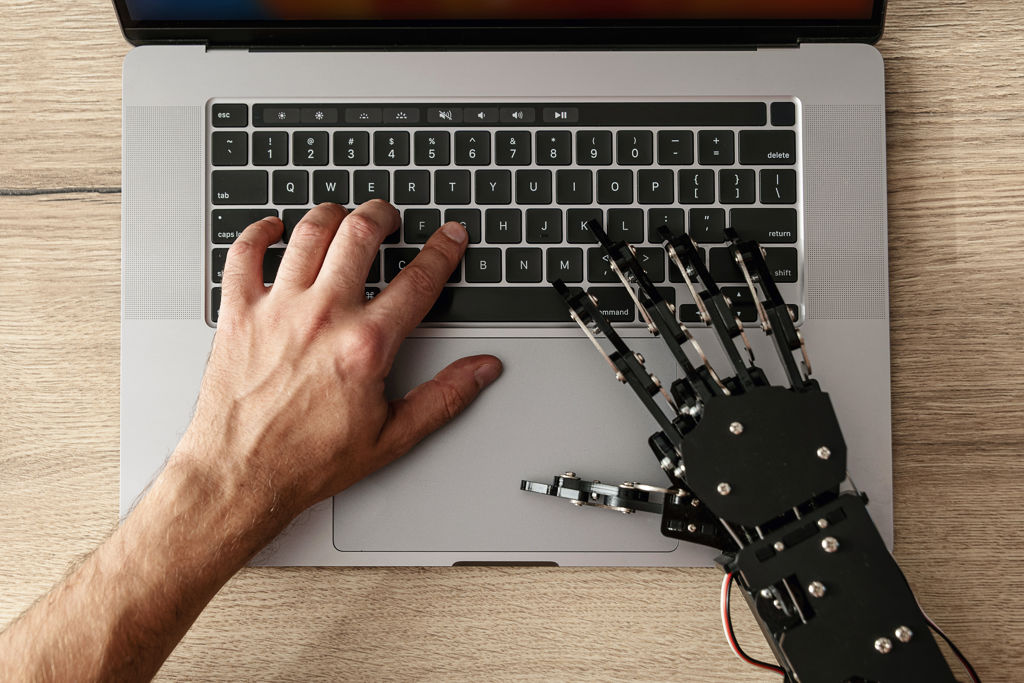 Menselijke hand en robothand op laptop