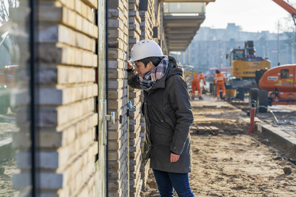 Vrouw kijkt in raam van huis dat wordt gebouwd op bouwplaats
