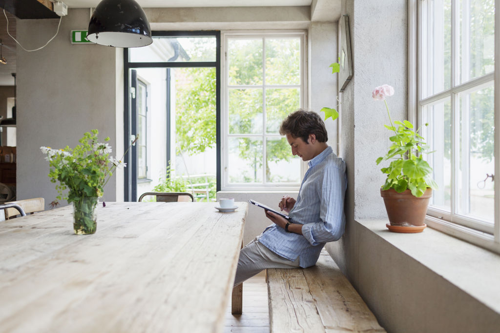 Man aan keukentafel op tablet