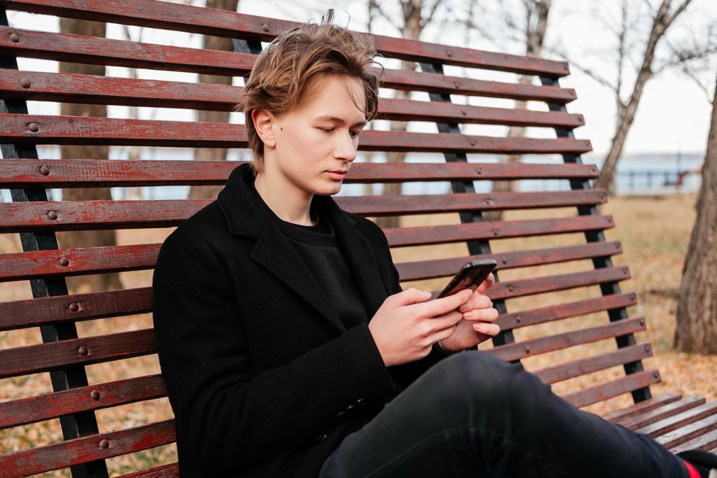 Jongere op een bankje op telefoon