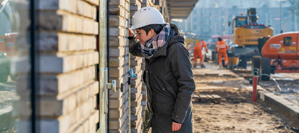 Vrouw kijkt in raam van huis dat wordt gebouwd op bouwplaats