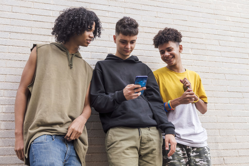 drie tieners kijkend naar een telefoon