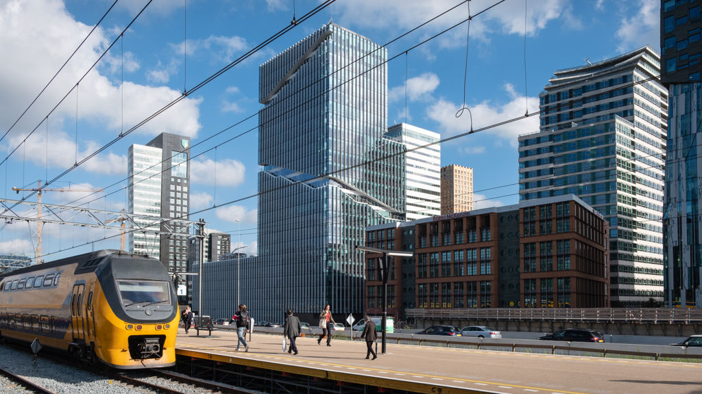 Trein staat stil op de Zuidas in Amsterdam met kantoorgebouwen op de achtergrond
