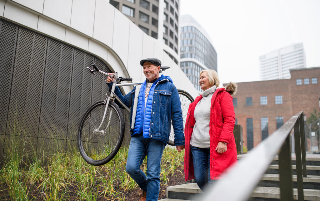 Blij koppel met fiets in de hand die en trap aflopen